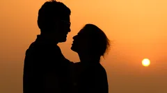 Silhouette d'une femme avec lunettes de soleil au coucher du soleil, vue romantique